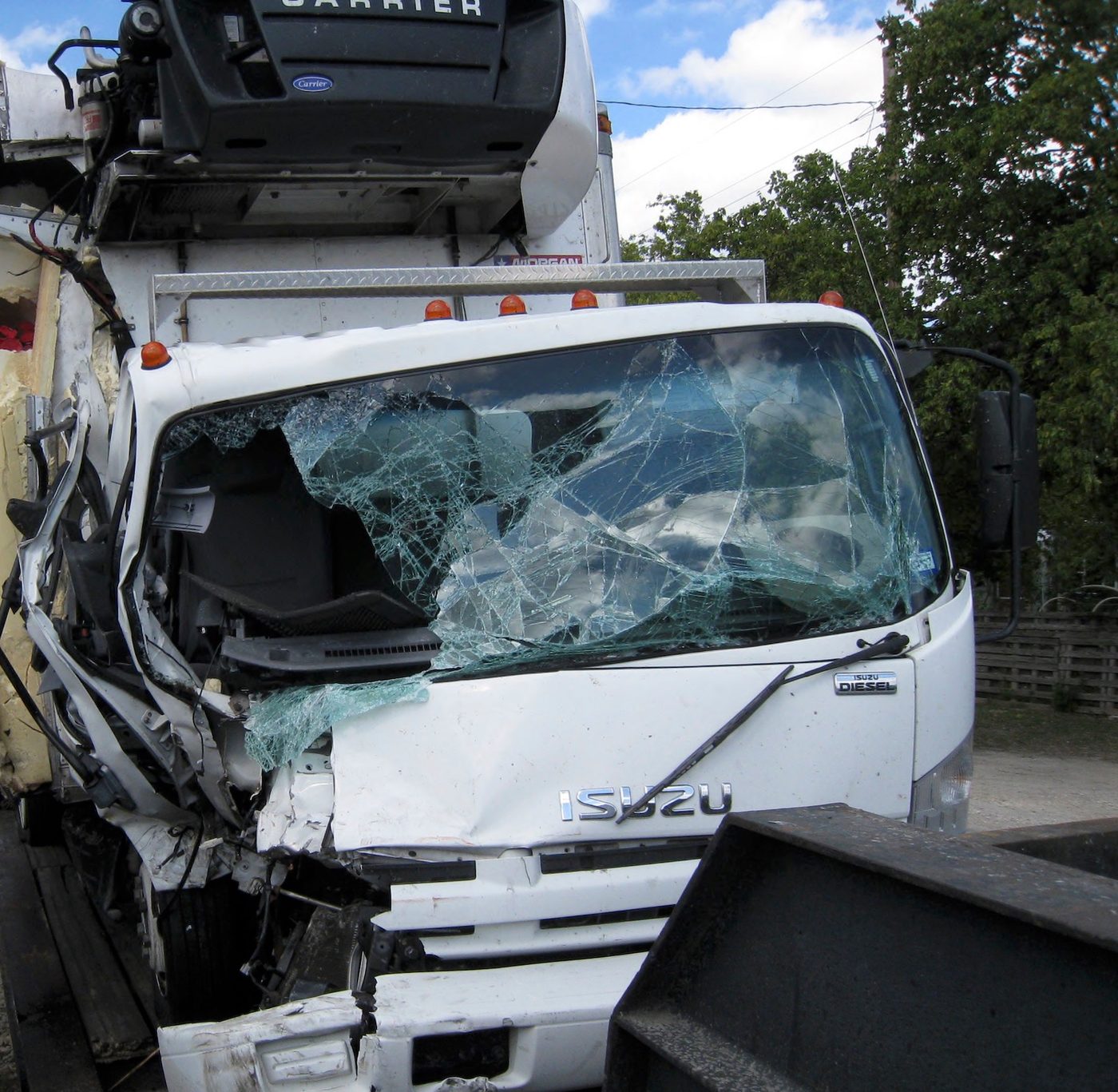 The severely damaged cab of a commercial box truck after a collision